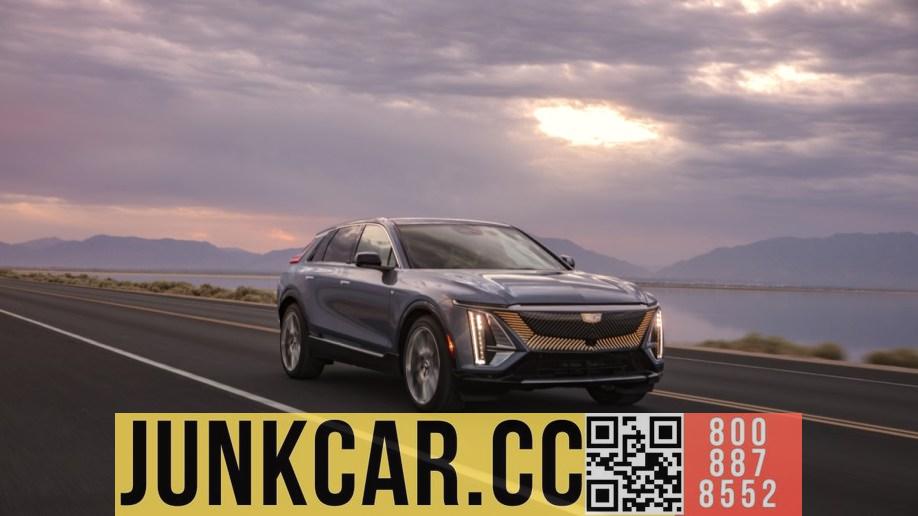 The 2024 Cadillac Lyriq electric SUV rides through the pink sunrise. The car is silver. Viewed from a diagonal forward angle, slightly to the right.